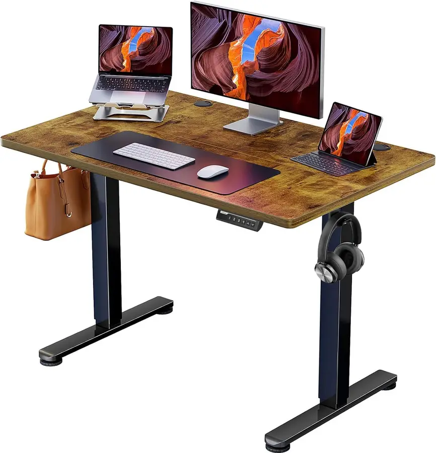 Escritorio elevable ErGear 100x60 cm en color marrón y negro con monitor y accesorios.