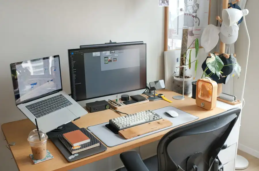 Escritorio eléctrico elevable en ambiente creativo, con doble monitor, portátil y accesorios de diseño en un espacio funcional y natural.