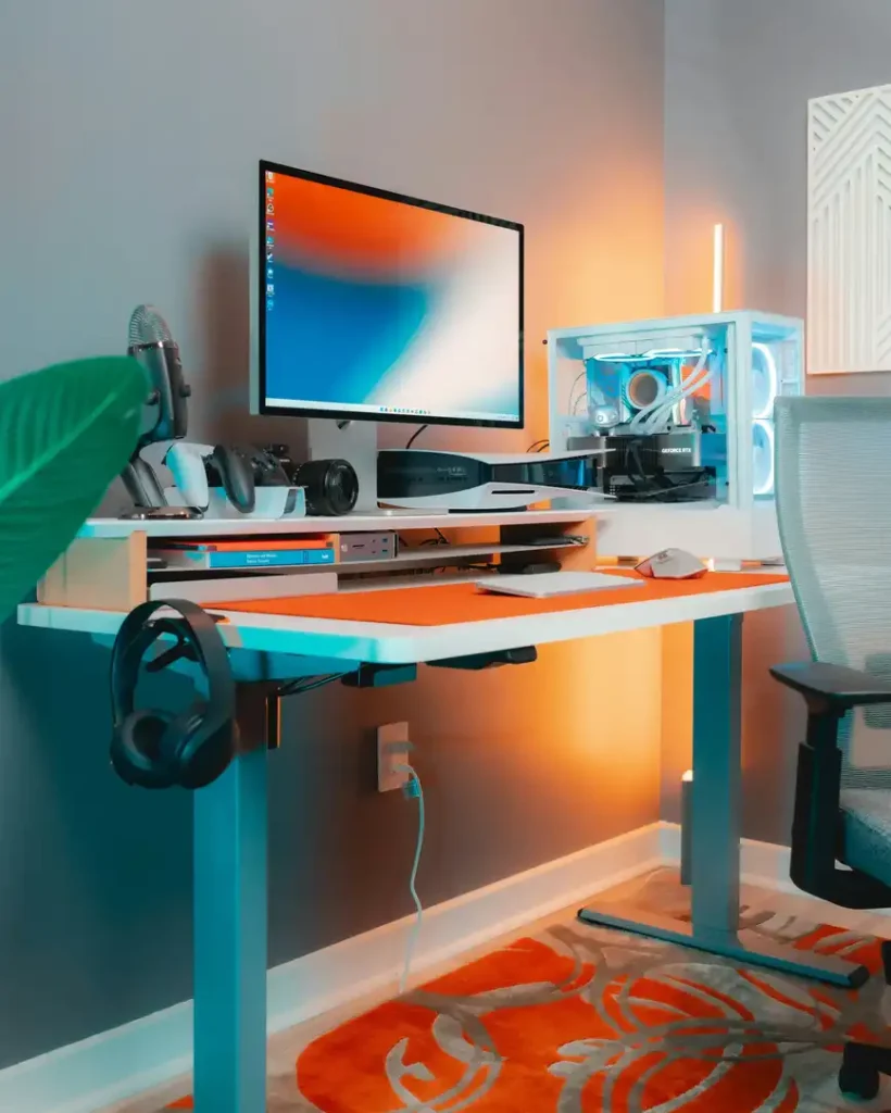 espacio-trabajo-organizado-escritorio-elevable Espacio de trabajo moderno con escritorio elevable blanco y setup gaming ordenado